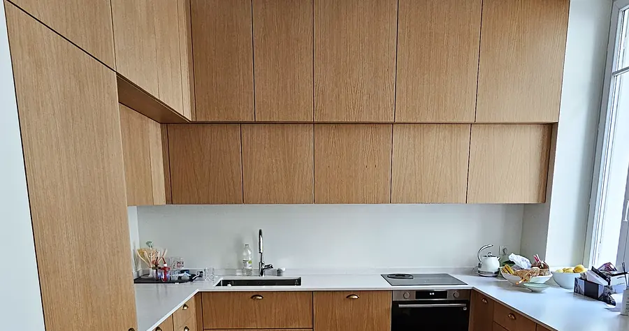 Détail d'une cuisine sur mesure en chêne clair avec plan de travail blanc