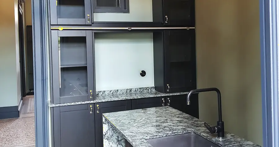 Plan de travail en granit veiné et îlot d'une cuisine sur mesure aux façades noires