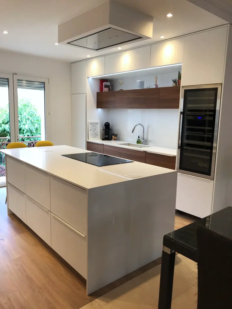 Cuisine blanche sur mesure avec îlot central, hotte plafond et cave à vin encastrée