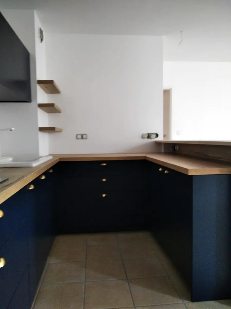 Cuisine en U sur mesure bleu nuit avec plan de travail en bois et étagères murales
