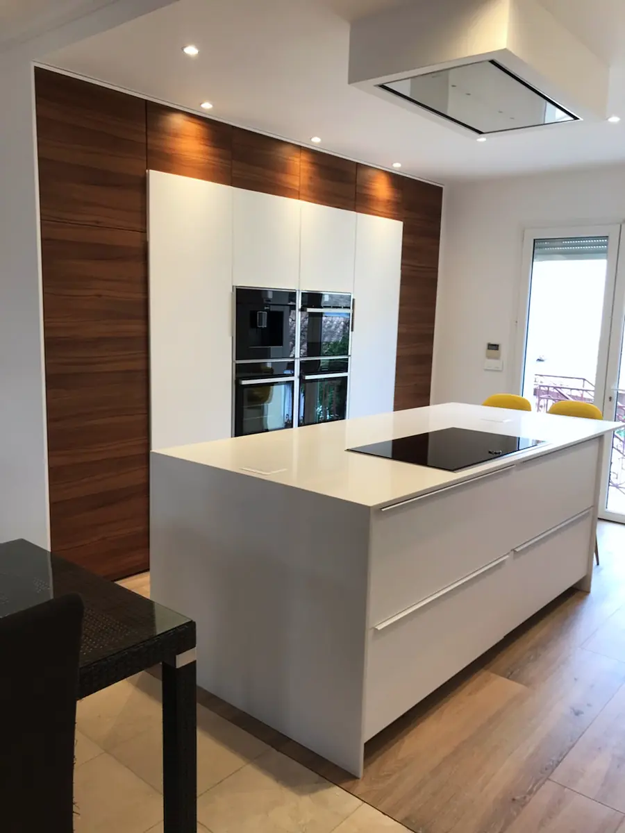 Cuisine sur mesure laquée blanche avec îlot central, plan de travail en quartz et placage bois toute hauteur