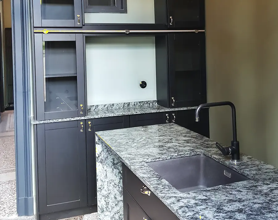 Cuisine sur mesure aux façades noires avec vitrines, plan de travail et joue en granit veiné gris