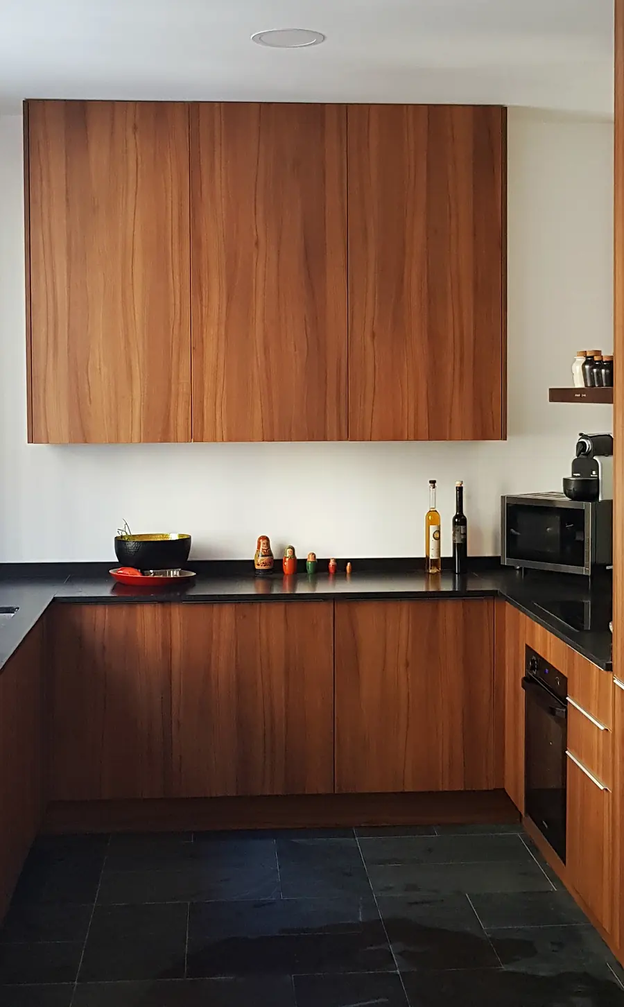 Cuisine sur mesure en placage noyer avec plan de travail en granit noir et sol en pierre naturelle