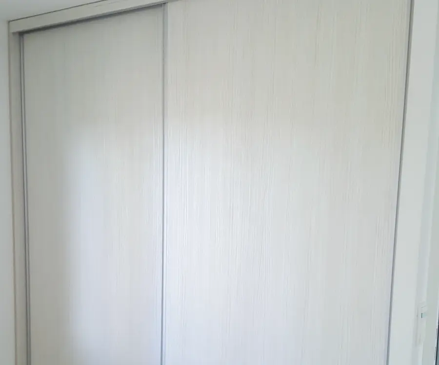 Dressing sur mesure à portes coulissantes laquées blanches, du sol au plafond