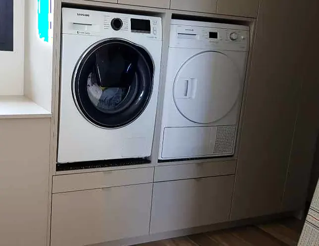 Buanderie sur mesure avec lave-linge et sèche-linge encastrés dans un meuble laqué blanc