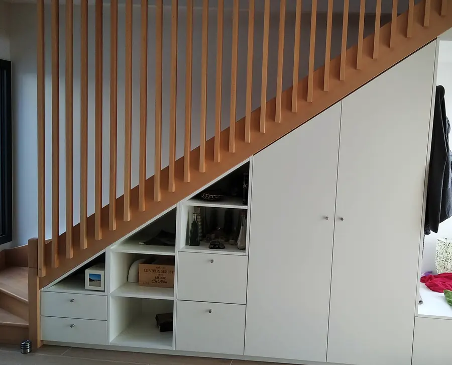 Rangement sur mesure sous escalier avec claustra en tasseaux de chêne, placards et niches intégrés