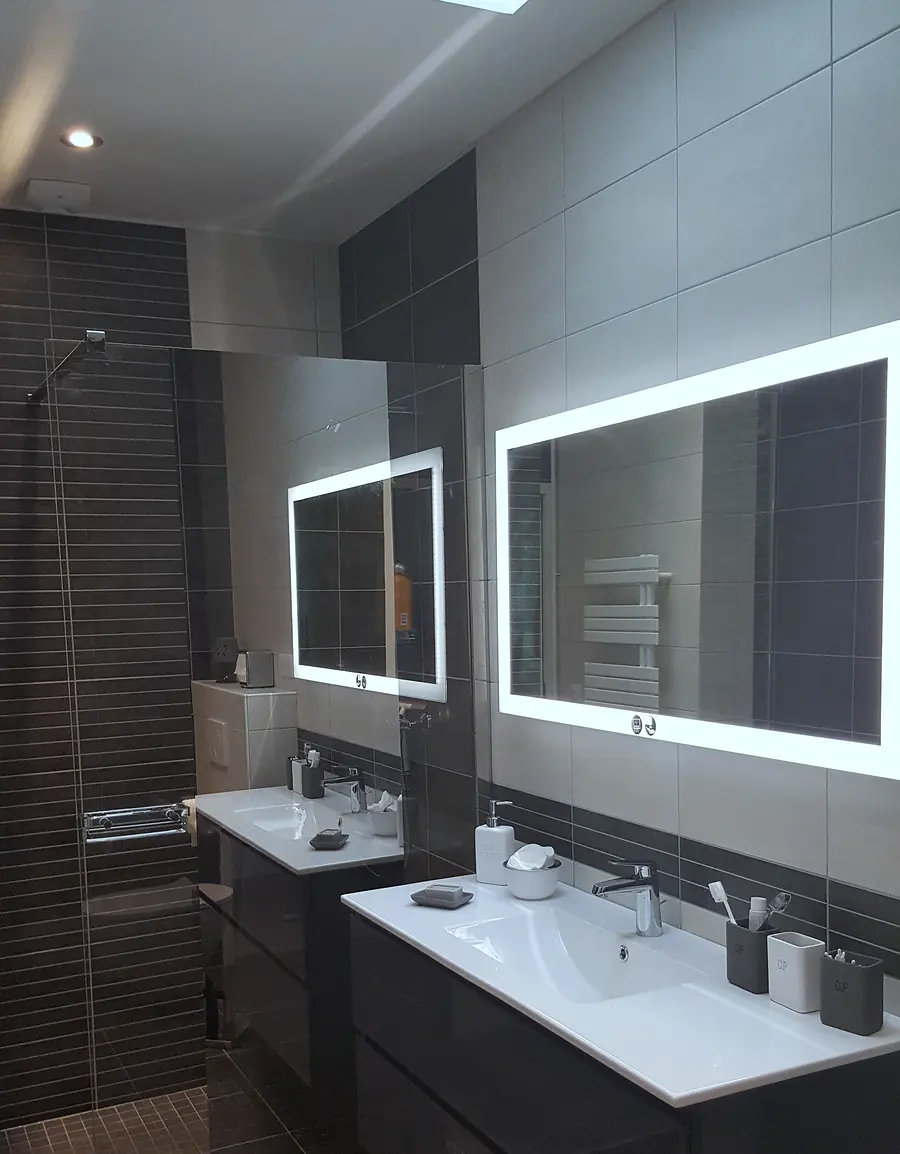 Salle de bain sur mesure avec meuble double vasque laqué foncé et miroirs rétroéclairés